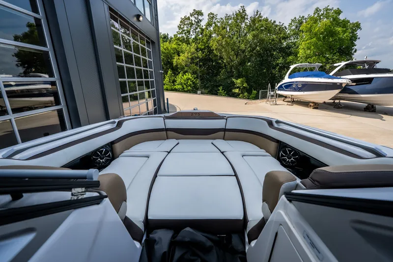 Slide: The Image of 2023 Yamaha Boats 275SE interior with luxurious seating, docked near other boats. - 21