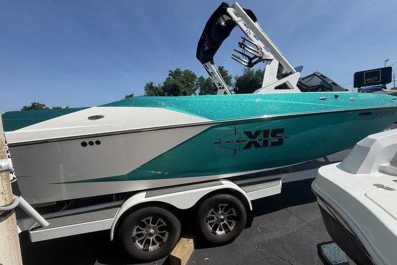 The Image of 2019 Axis A24 boat on trailer, teal and white design, parked outdoors. - 0