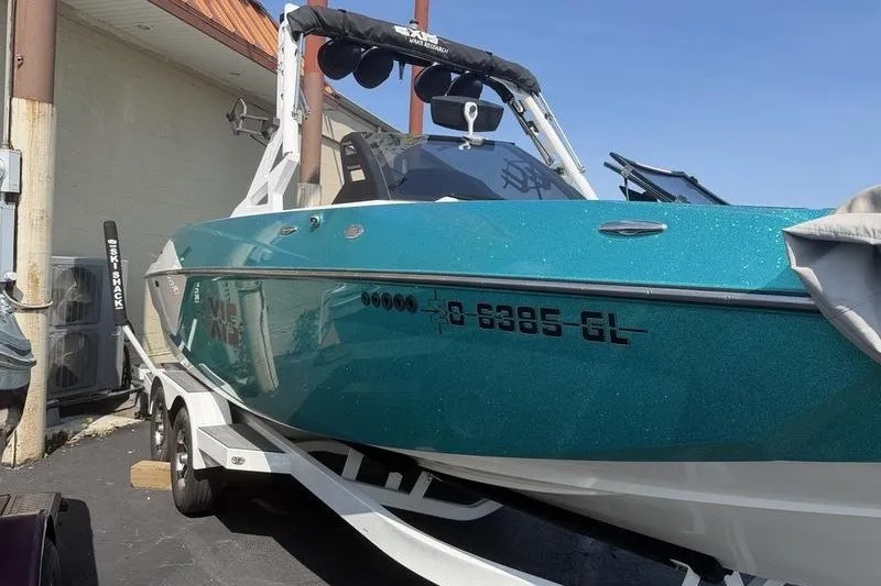 Slide: The Image of 2019 Axis A24 boat on trailer, teal color, parked outdoors. - 1
