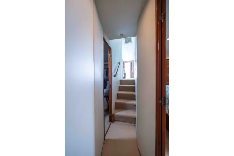 Slide: The Image of Narrow hallway with stairs inside 2005 Viking 56 Convertible yacht, featuring wooden doors. - 12