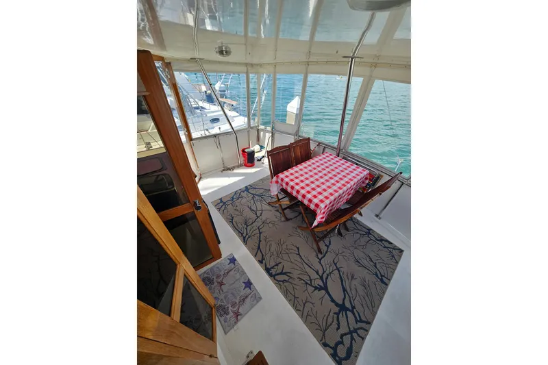 Slide: The Image of 1986 Jefferson 42 SE Sundeck Motor Yacht interior with dining area, checkered tablecloth, and ocean view. - 22