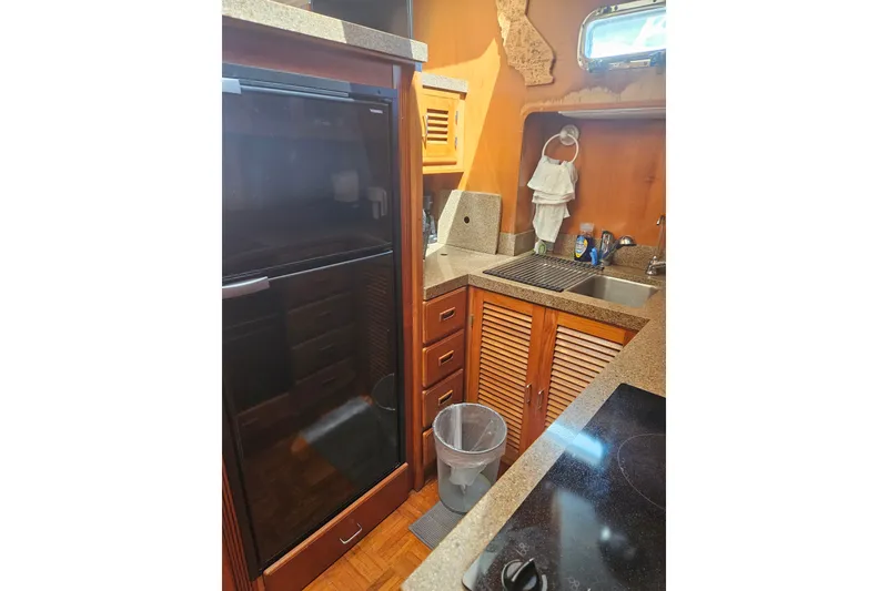 Slide: The Image of Compact kitchen in 1986 Jefferson 42 SE Sundeck Motor Yacht with wood cabinetry and modern appliances. - 20