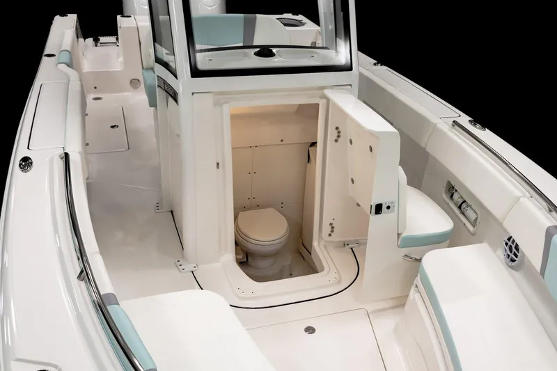 Slide: The Image of Manufacturer Provided Image: 2025 Robalo R250 Center Console boat interior with open console door revealing a compact marine toilet. - 3