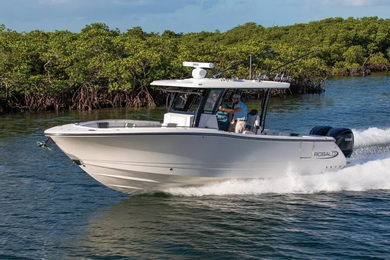 Slide: The Image of Manufacturer Provided Image: 2025 Robalo R300 Center Console boat cruising on water near lush mangroves. - 2