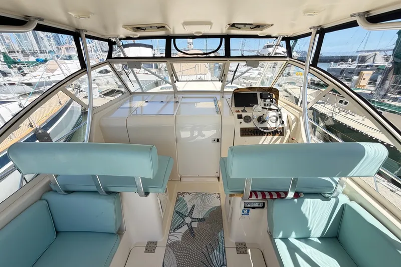 Slide: The Image of Interior of 2006 Mainship Pilot 34 Sedan with helm, seating, and marina view. - 9