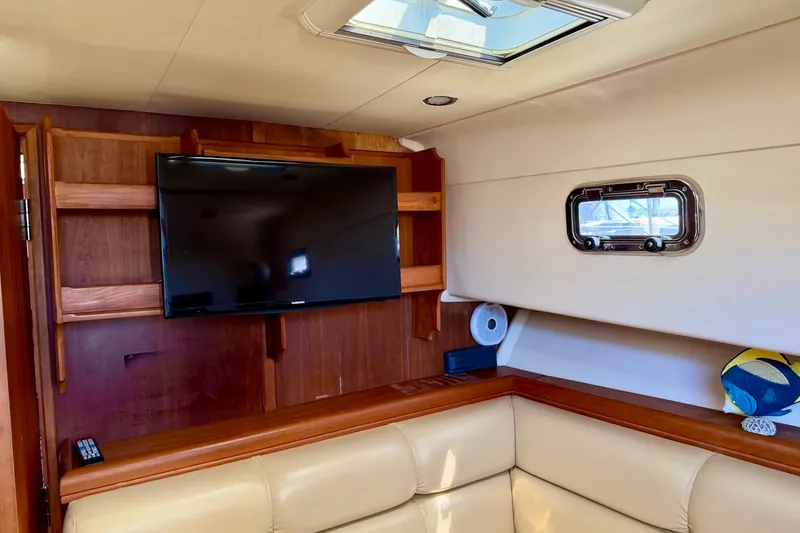 Slide: The Image of Interior of 2006 Mainship Pilot 34 Sedan with TV, wooden shelves, and porthole window. - 17