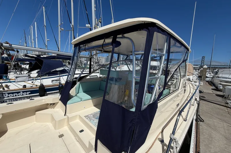 Slide: The Image of 2006 Mainship Pilot 34 Sedan docked at marina, featuring enclosed cockpit and seating area. - 5