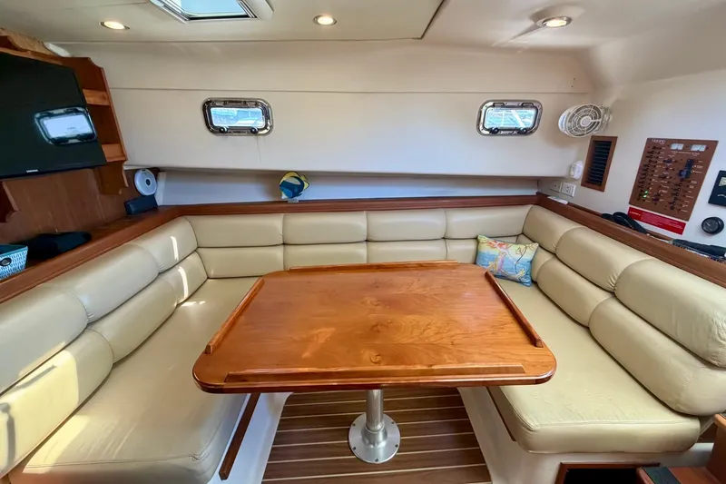 Slide: The Image of Interior of 2006 Mainship Pilot 34 Sedan with beige seating and wooden table. - 16