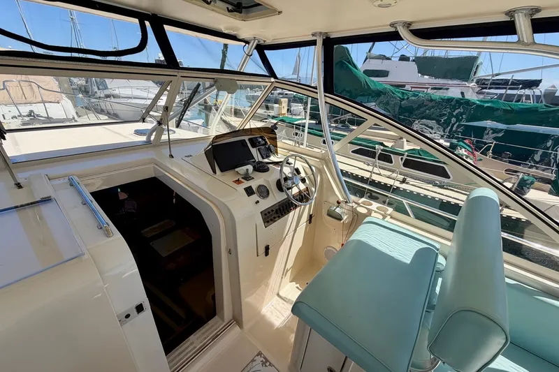 Slide: The Image of 2006 Mainship Pilot 34 Sedan interior with helm, marina view, and seating. - 11