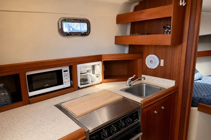 Slide: The Image of 2006 Mainship Pilot 34 Sedan galley with microwave, coffee maker, sink, and stove. - 15