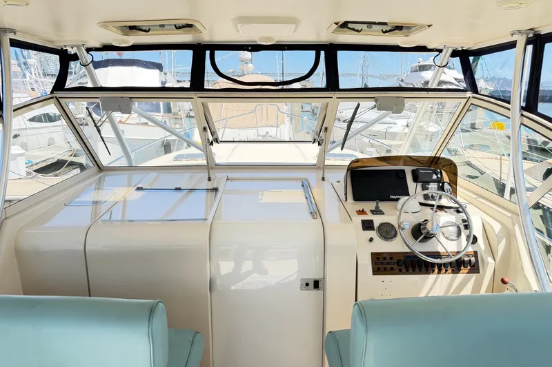 Slide: The Image of 2006 Mainship Pilot 34 Sedan helm with steering wheel, navigation controls, and marina view. - 8