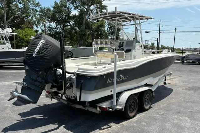 Slide: The Image of 2017 NauticStar 231 Coastal boat on trailer with Evinrude engine, parked outdoors. - 2