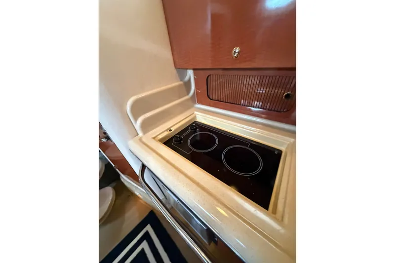 Slide: The Image of 2004 Sea Ray Sundancer 320 yacht kitchen with sleek stovetop and wooden cabinetry. - 23