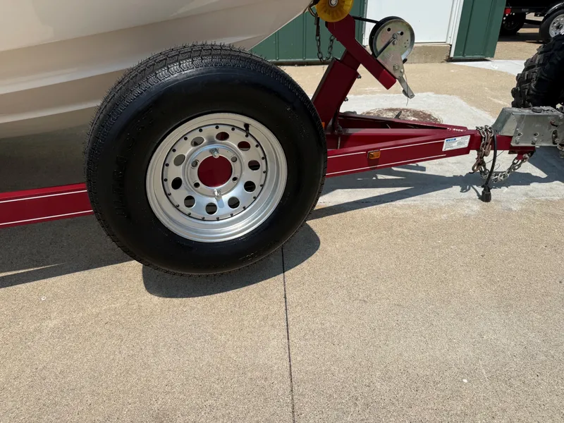 Slide: The Image of A red boat trailer with a large black tire is on a concrete surface. - 25