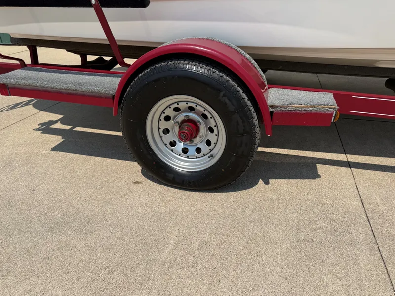 Slide: The Image of A red boat trailer with a large black tire on a concrete surface. - 24