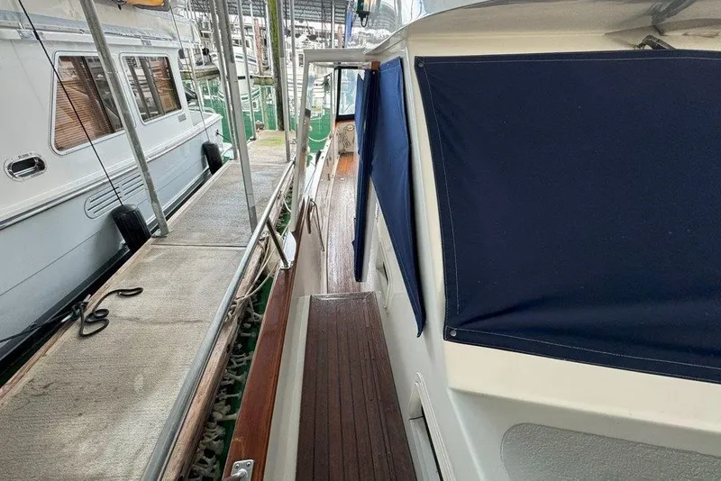 Slide: The Image of 1983 Ocean Alexander 40 Europa yacht docked, featuring wooden deck and blue canvas covers. - 36