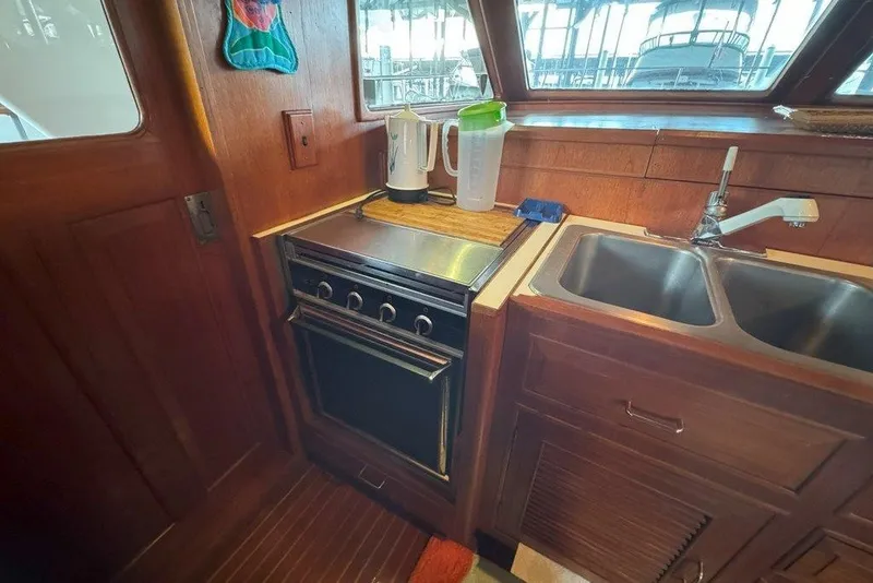 Slide: The Image of 1983 Ocean Alexander 40 Europa yacht kitchen with stove, sink, and wooden cabinetry. - 10
