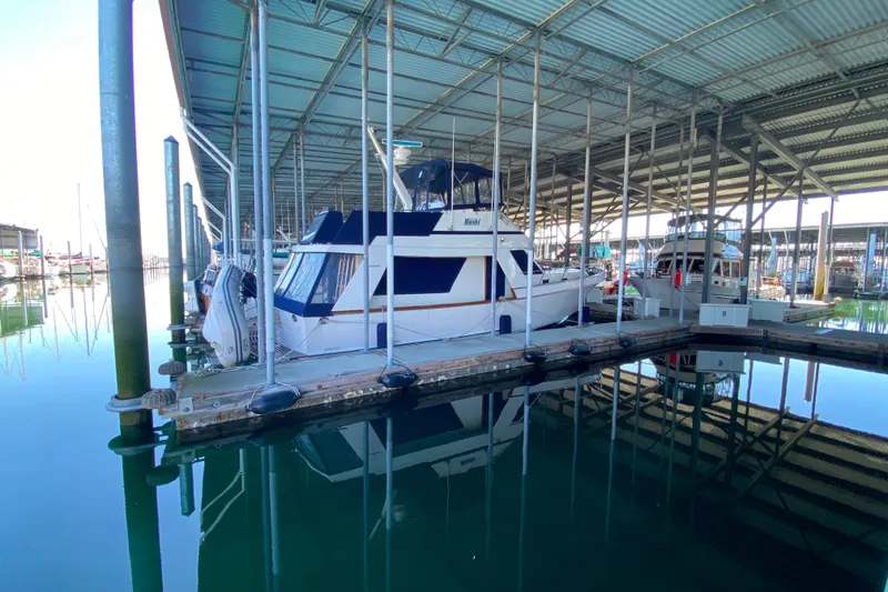 Slide: The Image of 1983 Ocean Alexander 40 Europa yacht docked in a covered marina, reflecting on calm water. - 2