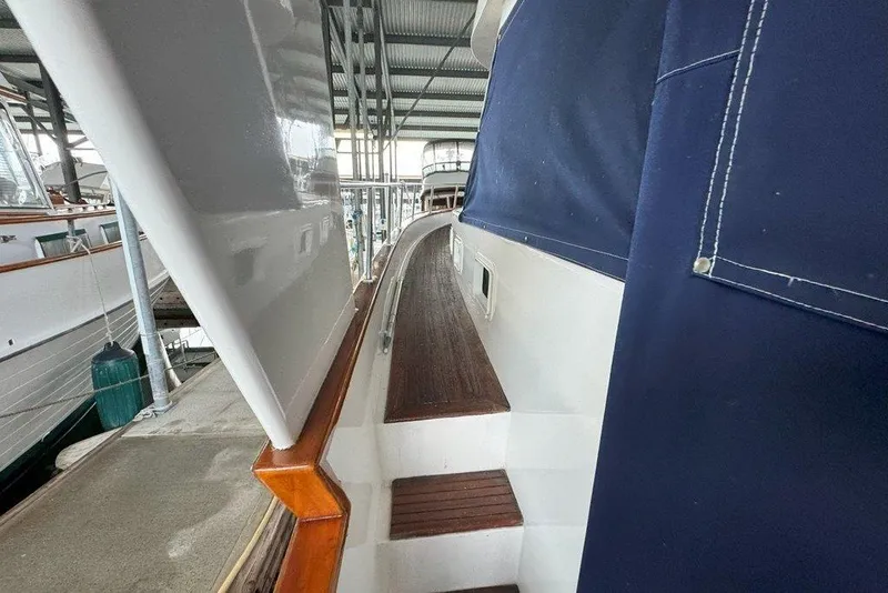 Slide: The Image of 1983 Ocean Alexander 40 Europa yacht docked, showcasing side deck and blue canvas cover. - 30