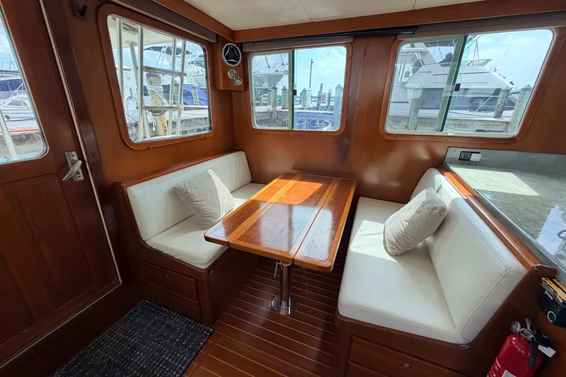 Slide: The Image of Cozy dining area in a 2005 North Pacific 42 boat with wooden table and cushioned seating. - 17