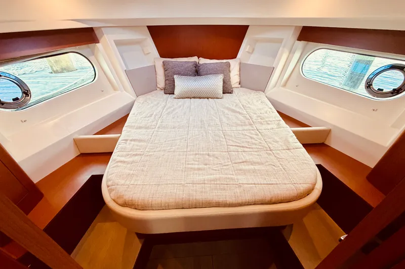 Slide: The Image of Cozy cabin interior of 2019 Beneteau Swift Trawler 30 with comfortable bed and porthole windows. - 25