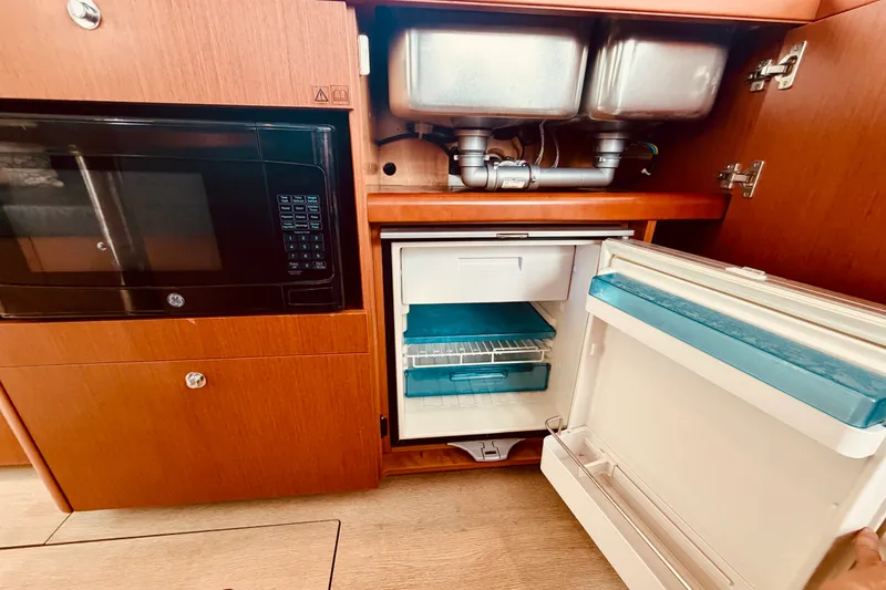 Slide: The Image of 2019 Beneteau Swift Trawler 30 kitchen with microwave, sink, and open refrigerator. - 18
