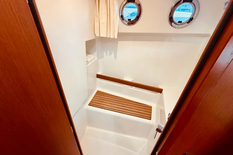 Slide: The Image of Interior of 2019 Beneteau Swift Trawler 30 bathroom with wooden bench and porthole windows. - 26