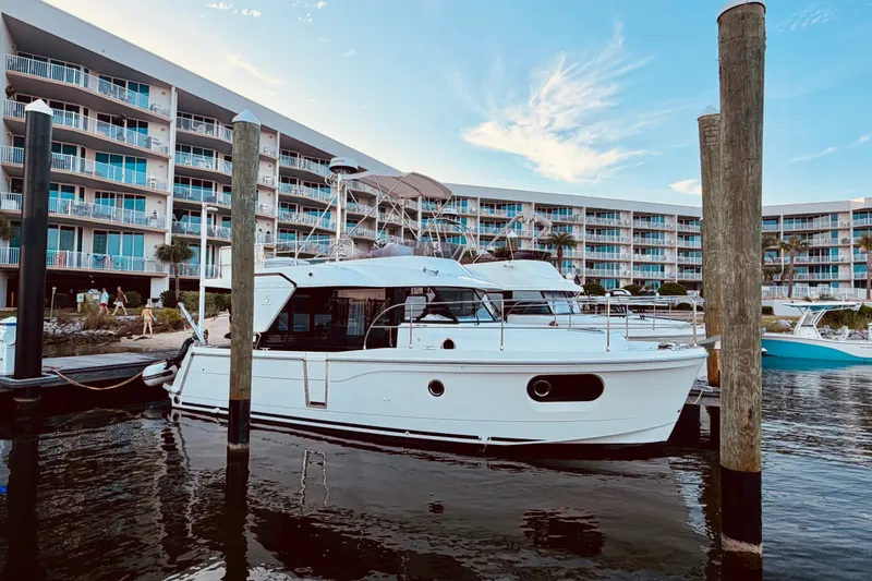The Image of 2019 Beneteau Swift Trawler 30 docked near waterfront apartments. - 0