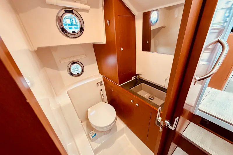 Slide: The Image of 2019 Beneteau Swift Trawler 30 bathroom with wooden cabinetry and porthole windows. - 27
