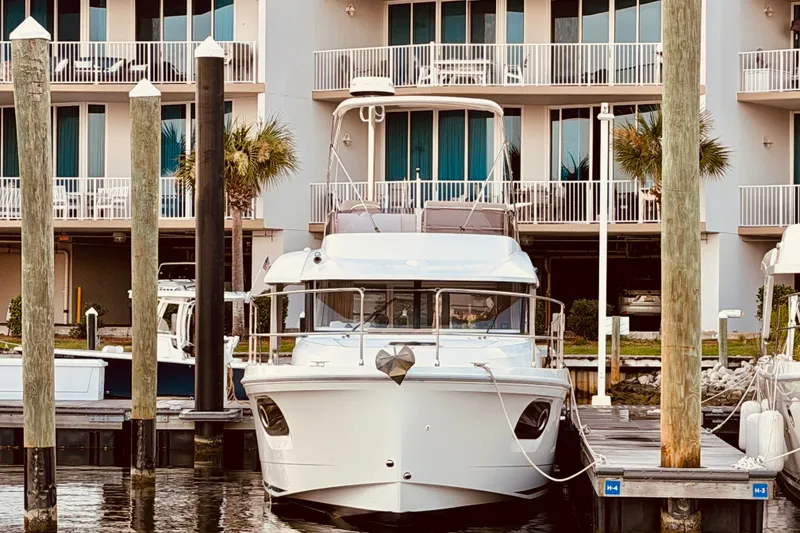 Slide: The Image of 2019 Beneteau Swift Trawler 30 docked at marina, with waterfront apartments in background. - 1