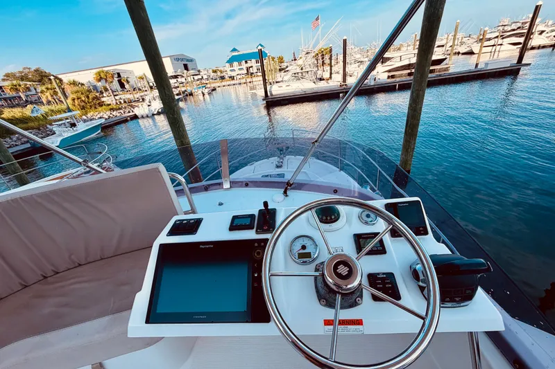 Slide: The Image of Helm of 2019 Beneteau Swift Trawler 30 at marina, showcasing navigation equipment and serene waters. - 7