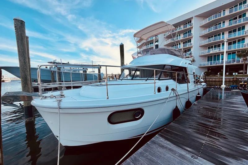 Slide: The Image of 2019 Beneteau Swift Trawler 30 docked at marina, modern design, clear blue sky. - 2
