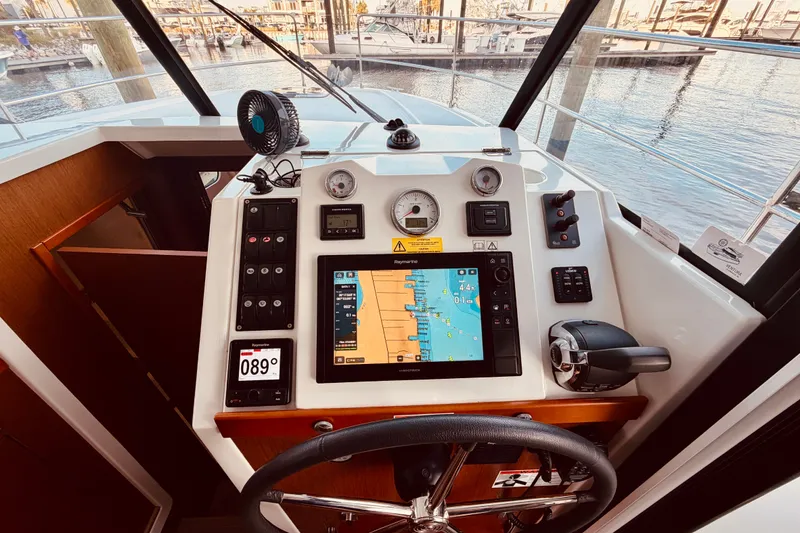 Slide: The Image of 2019 Beneteau Swift Trawler 30 helm with navigation display and controls, docked at marina. - 21