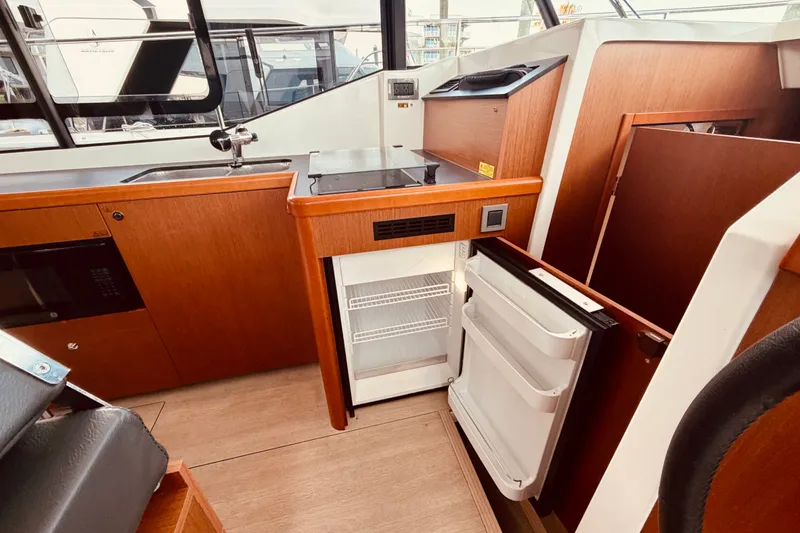 Slide: The Image of Interior of 2019 Beneteau Swift Trawler 30 with open fridge and wooden cabinetry. - 19