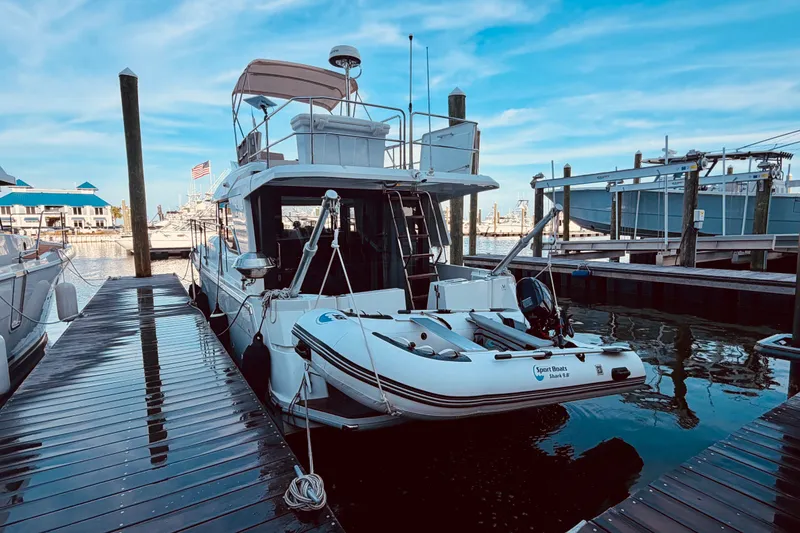 Slide: The Image of 2019 Beneteau Swift Trawler 30 docked with inflatable boat, under clear blue sky. - 4