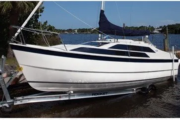 The Image of 2014 Tattoo 26 sailboat on trailer by the water, featuring sleek white and blue design. - 0