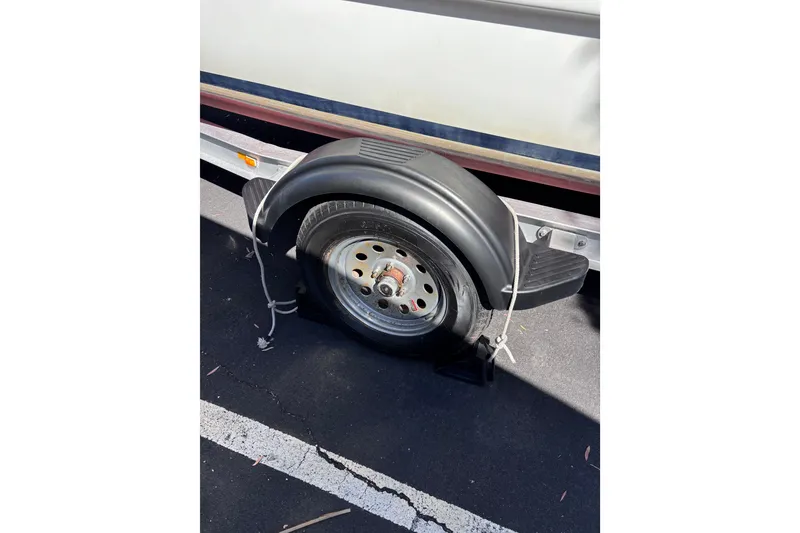Slide: The Image of Trailer wheel with black fender and rope, parked on asphalt. - 23