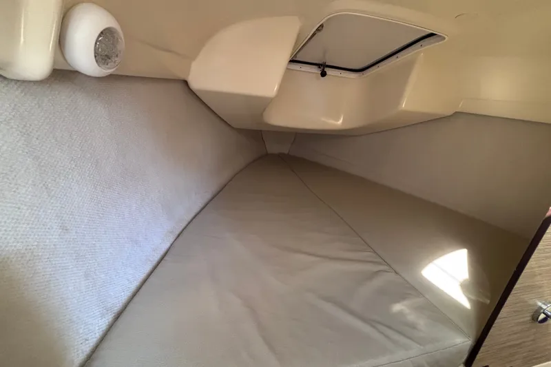 Slide: The Image of Compact cabin interior of a 2014 Tattoo 26 boat, featuring a cushioned sleeping area. - 14