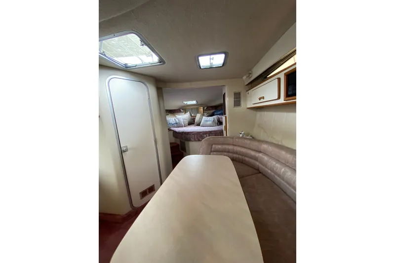 Slide: The Image of Interior of 1990 Sea Ray Sundancer 350, featuring cozy seating and a compact dining area. - 20