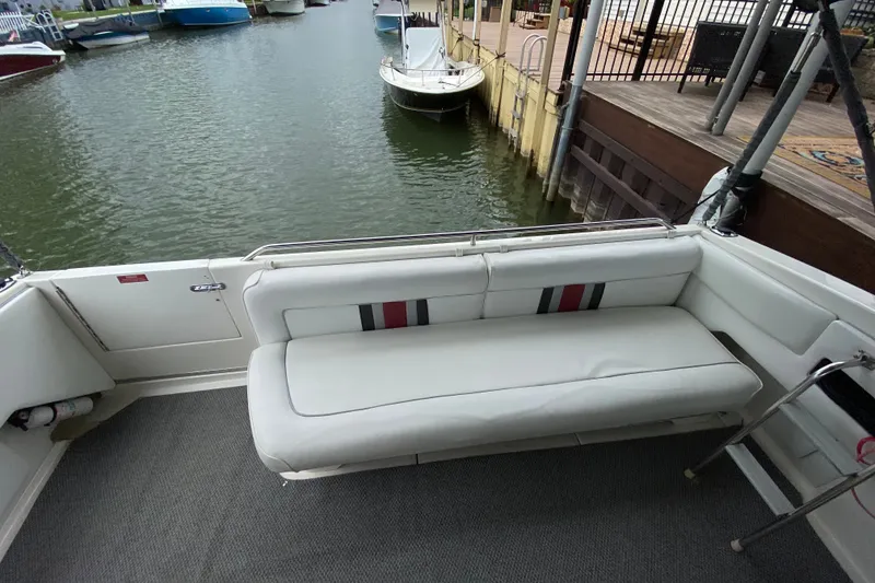 Slide: The Image of 1990 Sea Ray Sundancer 350 boat interior with white seating, docked by the water. - 15