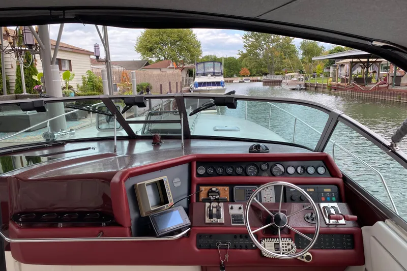 Slide: The Image of Cockpit view of a 1990 Sea Ray Sundancer 350, docked in a serene canal setting. - 13