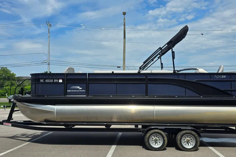 Slide: The Image of 2022 Bennington SX 22 Fishing pontoon boat on trailer under blue sky. - 3