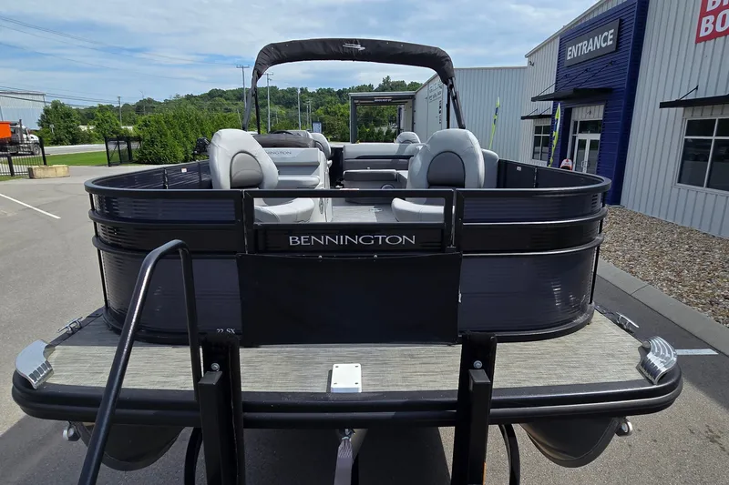 Slide: The Image of 2022 Bennington SX 22 Fishing pontoon boat displayed outdoors near dealership entrance. - 5