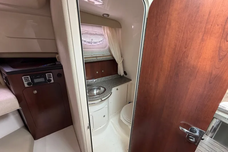 Slide: The Image of 2014 Robalo R305 Walkaround cabin interior with sink, toilet, and wood accents. - 26
