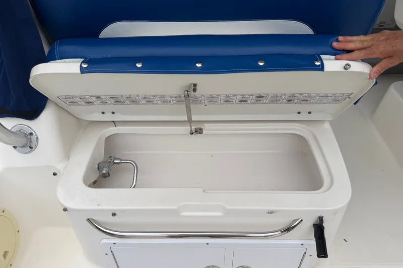 Slide: The Image of Open storage compartment on a 2014 Robalo R305 Walkaround boat with blue cushioned seat. - 31