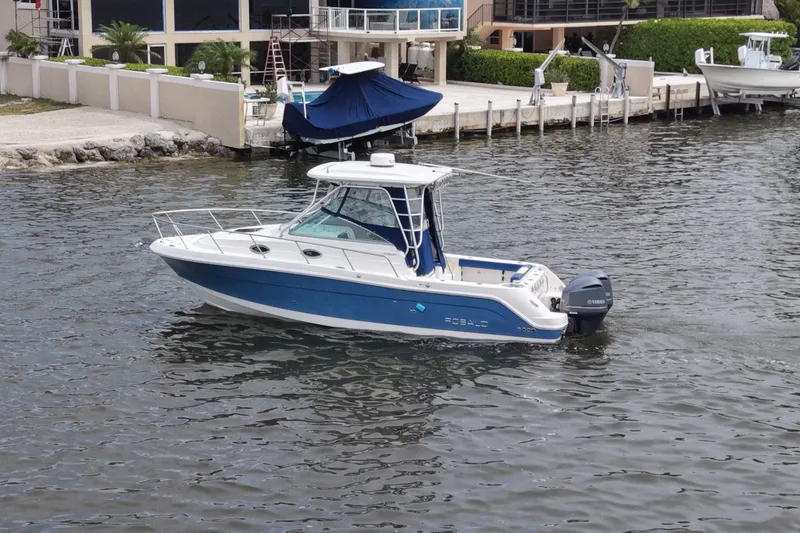 Slide: The Image of 2014 Robalo R305 Walkaround boat on water near a docked area. - 22