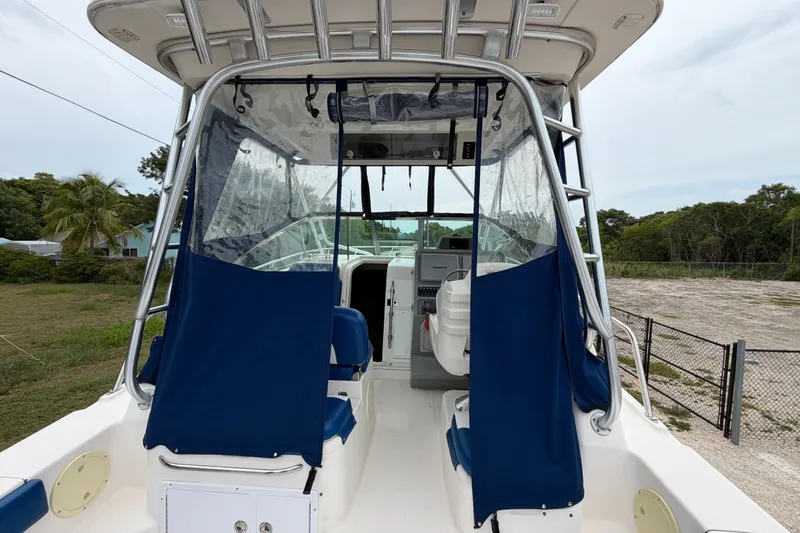 Slide: The Image of 2014 Robalo R305 Walkaround boat with blue covers and clear panels, docked outdoors. - 14