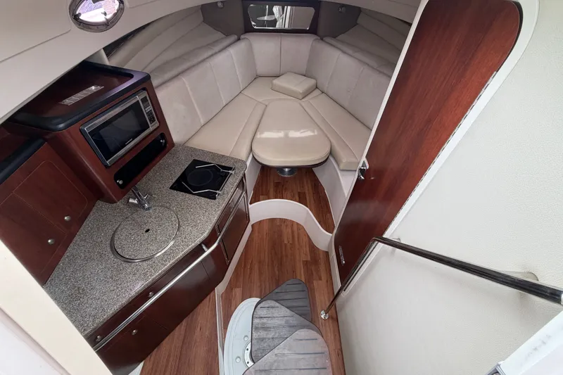 Slide: The Image of 2014 Robalo R305 Walkaround cabin interior with kitchenette, seating, and wood flooring. - 23