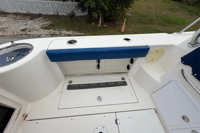 Slide: The Image of 2014 Robalo R305 Walkaround boat deck with blue cushioned seating and storage compartments. - 36