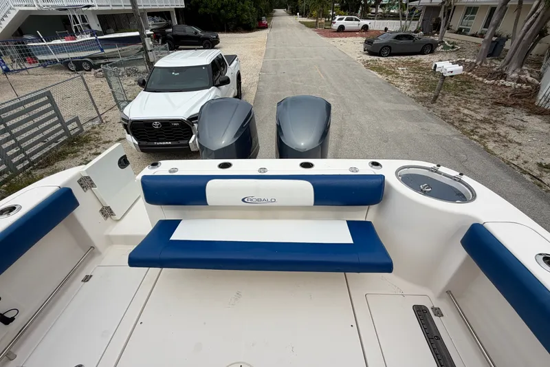 Slide: The Image of 2014 Robalo R305 Walkaround boat with blue seating, parked near vehicles. - 40